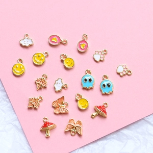 Macro view of assorted gold-plated enamel charms including smiley, clouds and maple leaf