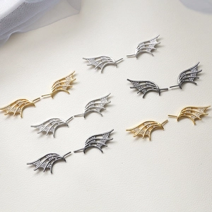 Macro detail of zircon-encrusted devil wing studs in gold, silver, and antique silver
