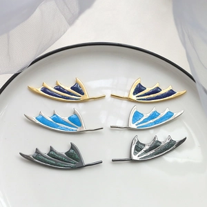 Macro detail of gold-plated wing charms with glitter enamel and baroque style accents