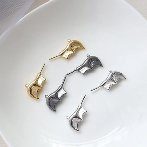 Detail of bat wing jewelry charms in gold, silver, and gunmetal with hammered texture