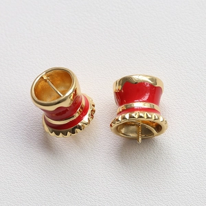 Dettaglio di ciondoli a forma di cappello in smalto rosso e ottone placcato oro
