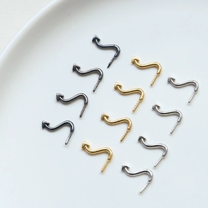 Macro view of S-shaped cat tail jewelry charms in gold, silver and gun black finishes