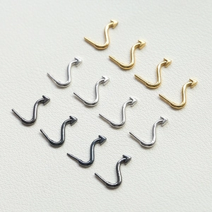 Detail of S-shaped curved arrow jewelry pieces in gold, silver and black metal finishes