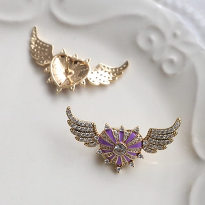 Detailed view of heart-shaped wing brooch with purple enamel and zircon accents