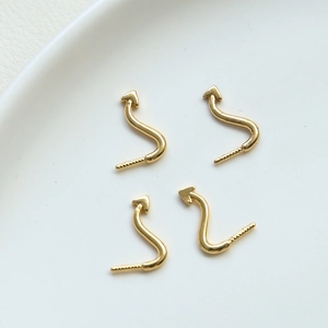 Detail of four gold-plated S-shaped jewelry connectors with arrows and screw threads