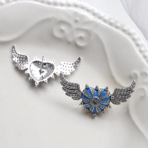 Macro view of blue enamel winged heart earring with cubic zirconia and metal backing