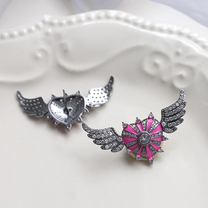 Detail view of pink heart wing earrings with cubic zirconia on a white vintage plate