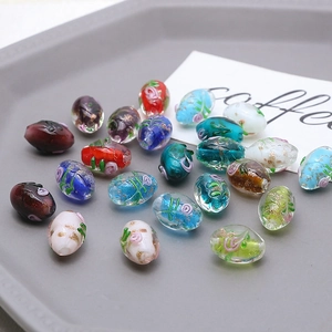 Macro detail of handmade oval glass beads with floral patterns and gold foil for DIY jewelry
