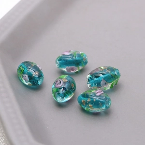 Macro shot of 5 teal vintage floral glass beads with gold foil for DIY jewelry making