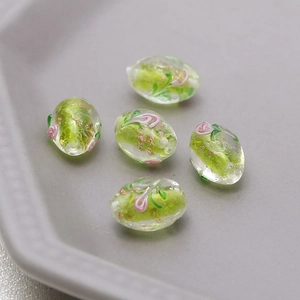 Macro shot of oval glass beads with pink 3D flower and gold foil for DIY jewelry