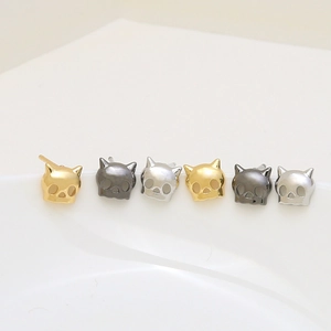 Cat skull earring set in gold, silver, and black finishes on white porcelain surface