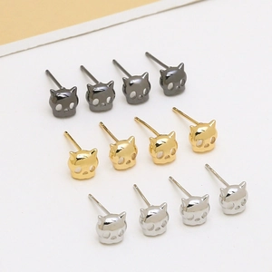Close-up of cat-shaped skull earring studs in gold, silver, and gunmetal finishes