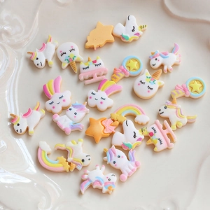 Nahaufnahme bunter Harz-Cabochons mit Einhorn- und Regenbogenmotiven für Bastelarbeiten