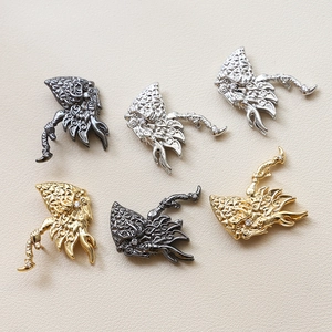 Macro view of detailed metal dragon charms with cubic zirconia and vintage filigree