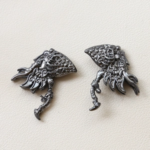 Detail of tribal style dark grey plated metal pendants with ornate engravings and small zircons