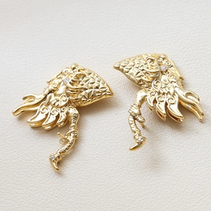 Macro shot of gold-plated dragon wing charms with zircon stones on white leather