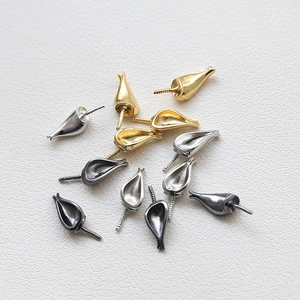 Detailed view of baroque fox-ear pearl peg pendants in gold, silver, and gun black finishes