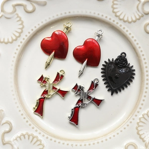 Detailed macro view of Gothic heart daggers and skull cross charms on a white plate