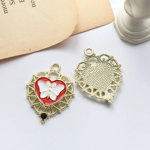 Detailed view of heart-shaped gold alloy pendant with red enamel and white butterfly detail