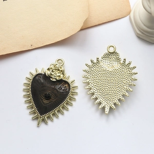 Detailed front and back views of heart charm with black enamel eye and golden rose detail