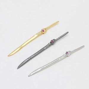 Detailed view of sword charms in gold, silver and black with small red gemstones