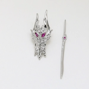 Macro detail of dragon head brooch and sword pin set with pink gemstones and silver finish