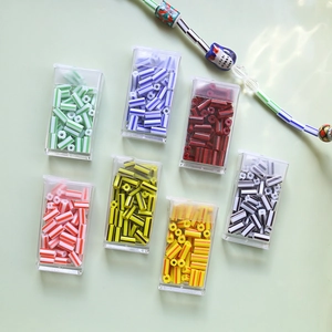 Detailed view of colorful striped tube beads for DIY jewelry making in individual boxes