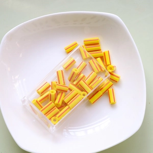 Close-up of yellow and red striped cylindrical beads for DIY jewelry making and crafts