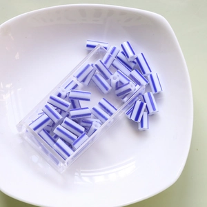 Close-up of blue and white striped tube beads in a clear box for DIY jewelry making