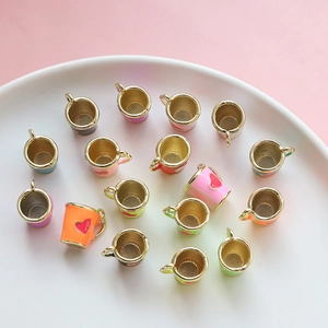 Dettaglio di mini ciondoli a forma di tazza con cuore smaltato per gioielli e fai-da-te