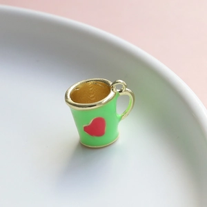 Vista macro di un ciondolo a mini tazza verde smaltata con cuore e bordo dorato