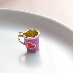 Dettaglio macro del ciondolo a forma di mini tazza viola con cuore rosso e oro