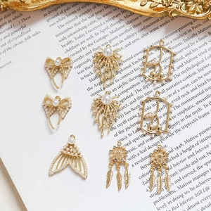 Detailed view of vintage gold pearl pendants including bow, fishtail and dreamcatcher charms