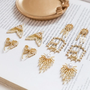 DIY jewelry charms featuring gold fish tails, bows and pearls on a vintage book background