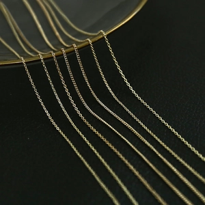 Macro view of detailed 14K gold plated cross and flat O-shaped DIY jewelry chains