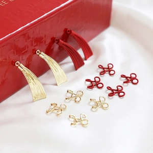 Gros plan de breloques éventails rouges et nœuds dorés pour bijoux artisanaux