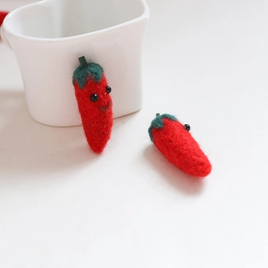 Detail einer handgefertigten roten Chili-Filzpuppe mit süßem Gesicht und grünem Stiel