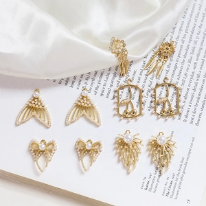 Golden fish tail and bow pearl charms for DIY jewelry making on vintage book background
