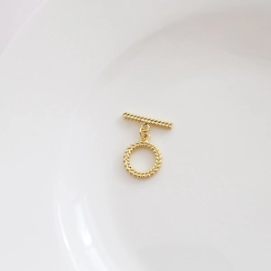Nahaufnahme des goldenen OT-Knebelverschlusses mit Spiralstruktur auf weißem Tablett