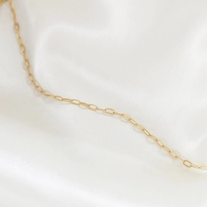 Macro di una catena a maglie ovali testurizzate placcata oro 14k su seta bianca