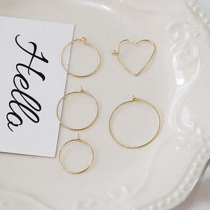 Detailed set of 14k gold-filled hoops and heart-shaped earrings on a white ceramic tray