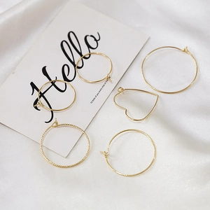 Detail view of 14K gold-filled earrings set with heart and twisted designs on white silk