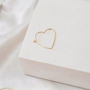 Detailed view of 14k gold-filled heart-shaped hoop earring on minimalist white display