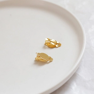 Macro detail of gold-plated DIY earring converters with round bases on a ceramic plate