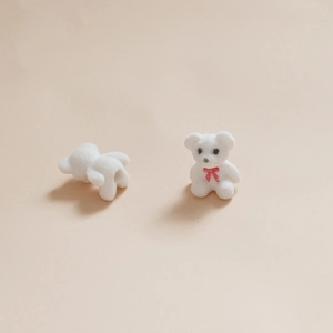 Gros plan sur des perles ours floquées blanches avec nœud rouge et trous de filetage