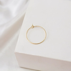 Detail of 14k gold-filled hoop earring with twisted texture on minimalist display