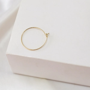 Macro view of gold hoop earring with textured spiral pattern and snap-lock closure