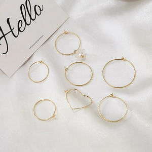 7-piece set of 14k gold-plated hoop earrings with heart and floral charms on white fabric