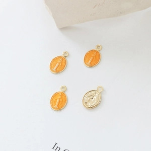 Makroansicht ovaler vergoldeter Jungfrau Maria Anhänger mit orangefarbenem Tropföl-Finish