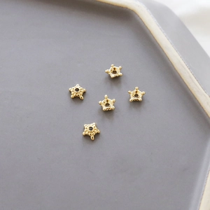 Vista macro de terminales de estrella bañados en oro 14K para joyería en bandeja cerámica